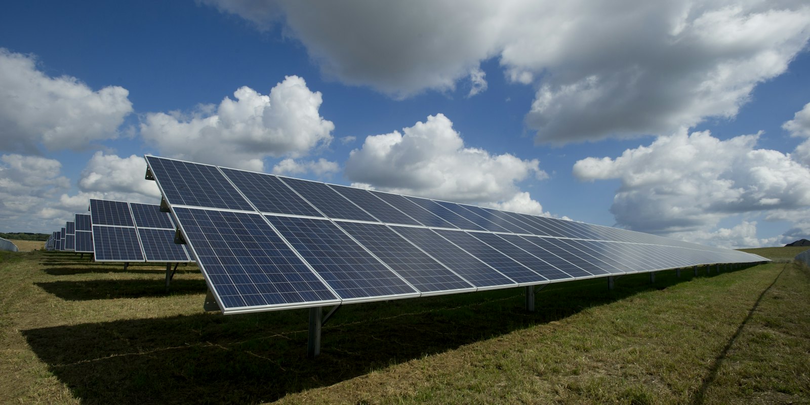 Solar panels in an open field under blue sky